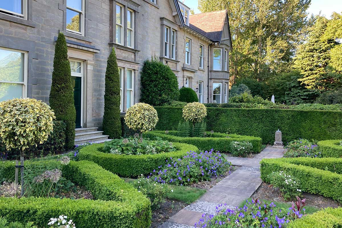 Garten im englischen Landhausstil mit immergrünen Pflanzen, Laubholz und Nadelgehölz